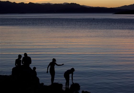Jeffery Serrano of Henderson, Nev., second from left, helps his kids fish at twilight at the edge of Kingman Wash at Lake Mead National Recreation Area, Ariz.